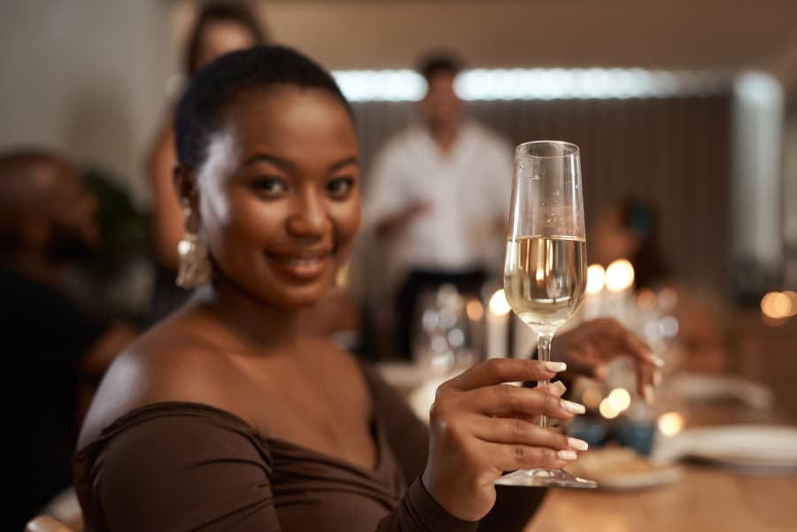 Woman at party holds up glass of Champagne